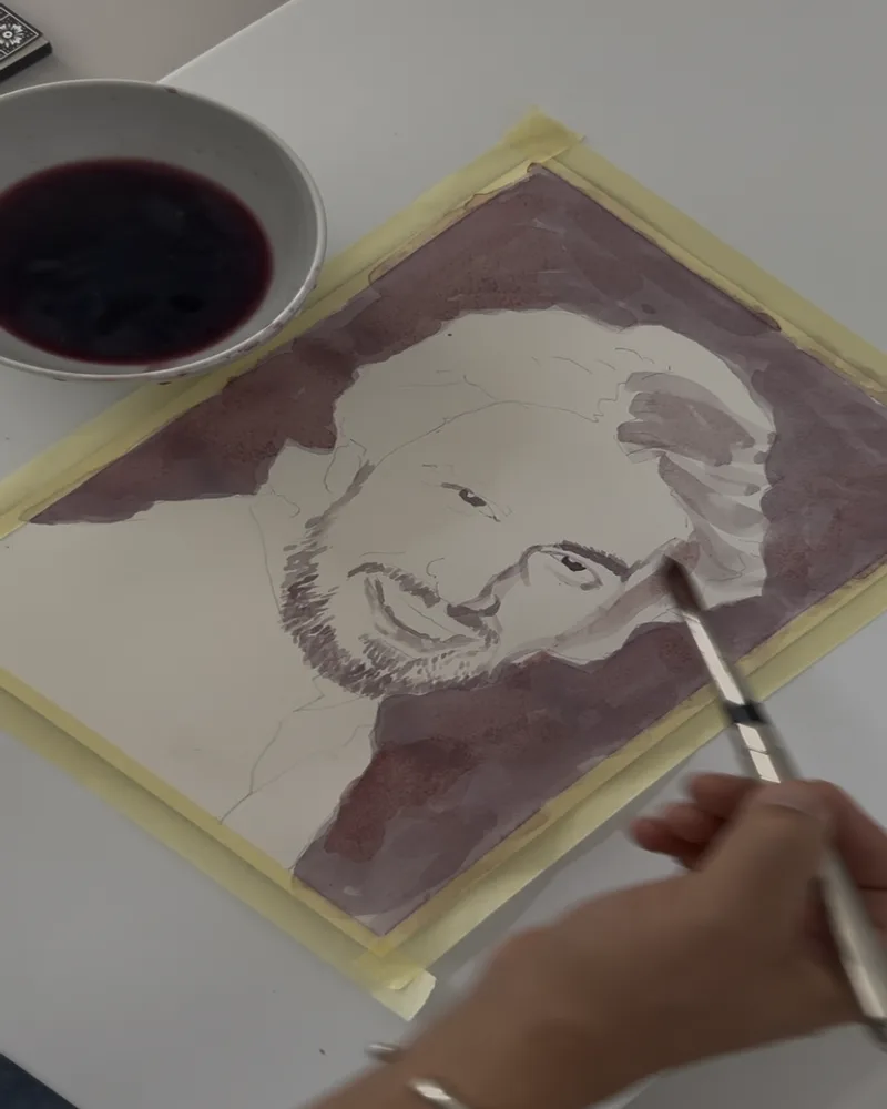 Mid-stage wine portrait in progress, artist hand painting with red wine